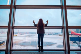 Girl watching planes through airport window