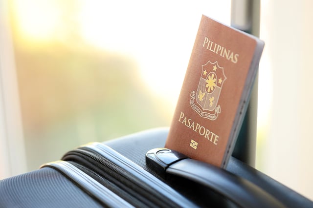 A Philippine Passport Lying Next To A Suitcase