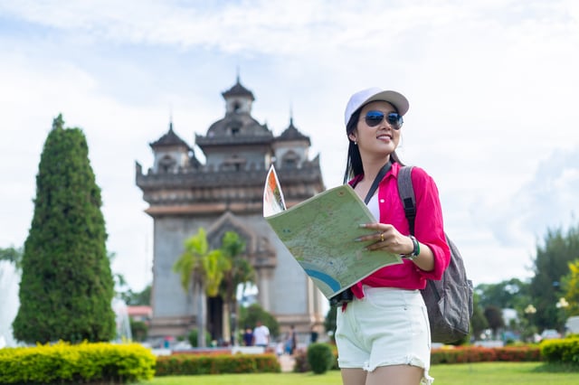 Junge Frau, die über einen hölzernen Weg durch grüne Reisfelder in der Nähe des Patuxai-Tors in Vientiane, Laos, geht