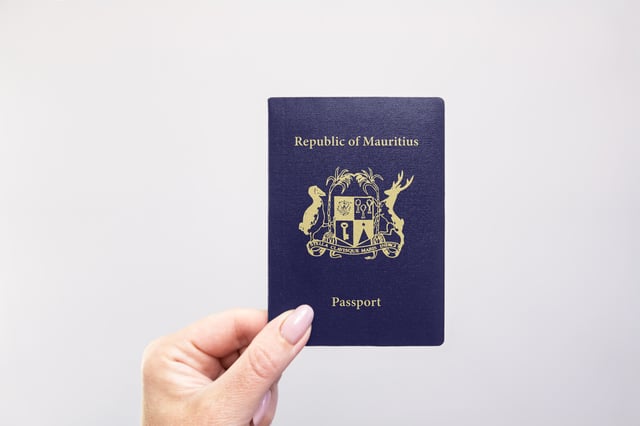 Mauritius Passport Held In Hand Against A Plain White Background