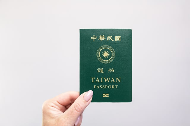 Passport Held In Hand Against A Plain White Background