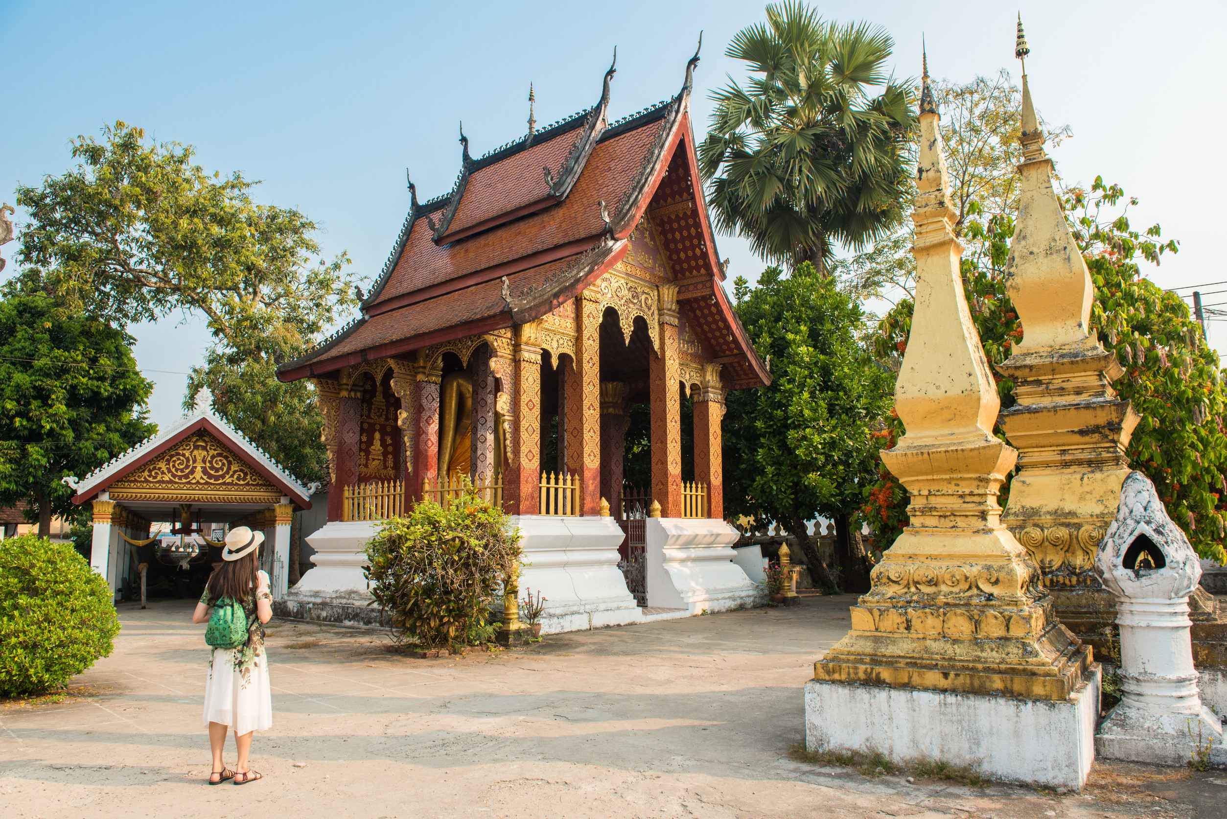 Woman walking on a wooden walkway among green rice fields near Patuxai Gate in Vientiane, Laos